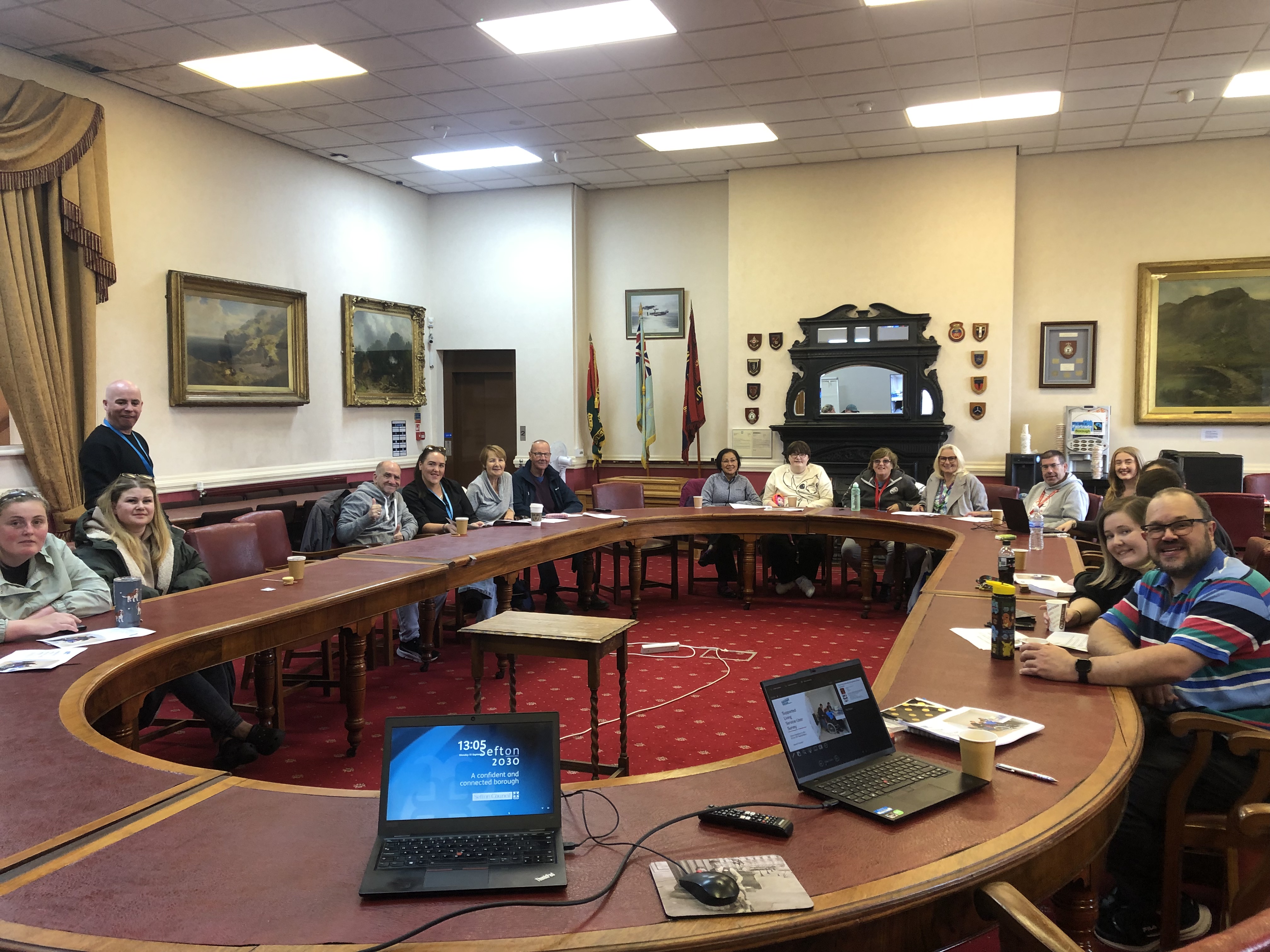 A room with people sitting at an oval table