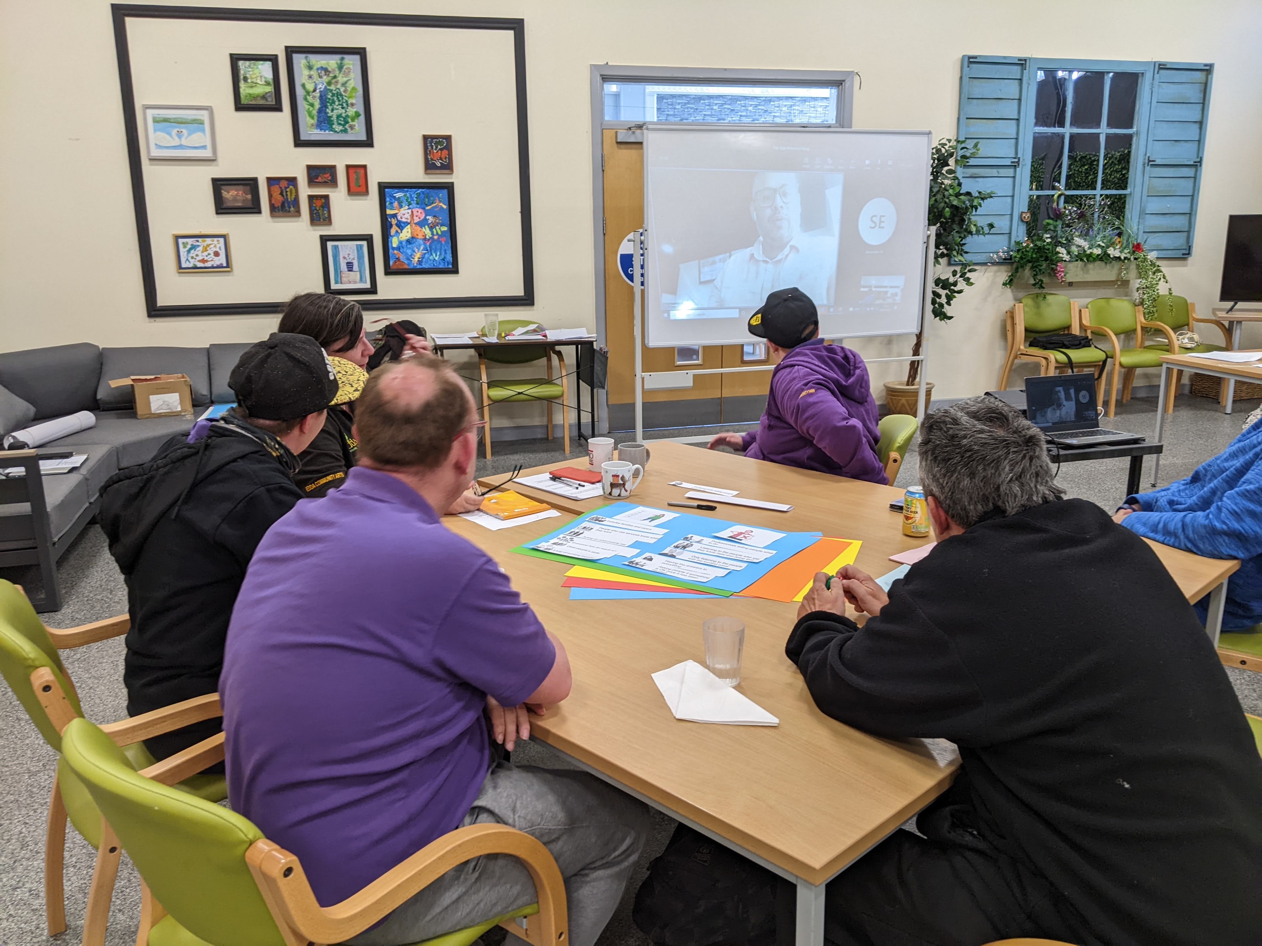 people sitting at a table looking at a tv screen
